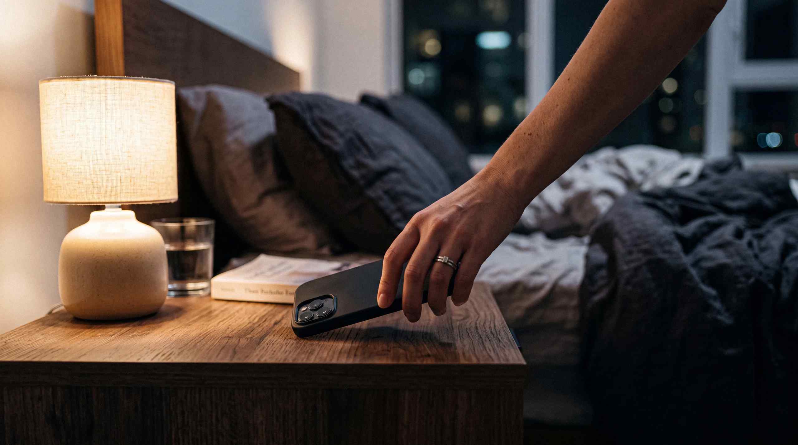 A person putting an smartphone on a bedside table before bed.